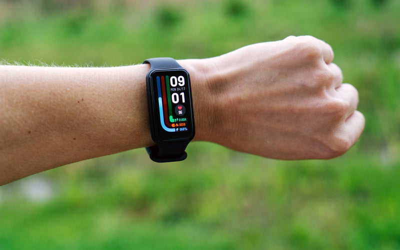Amazfit Band 7 budget fitness tracker on a wrist with a green background
