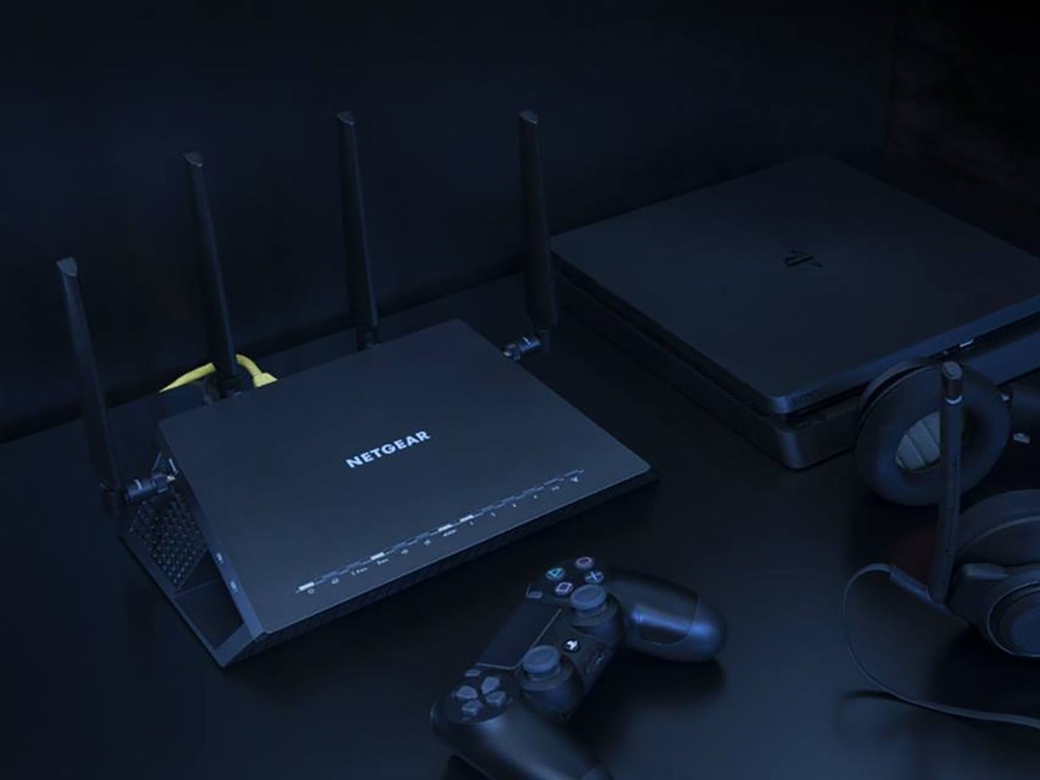 A Netgear router near a PlayStation video game console and headphones.